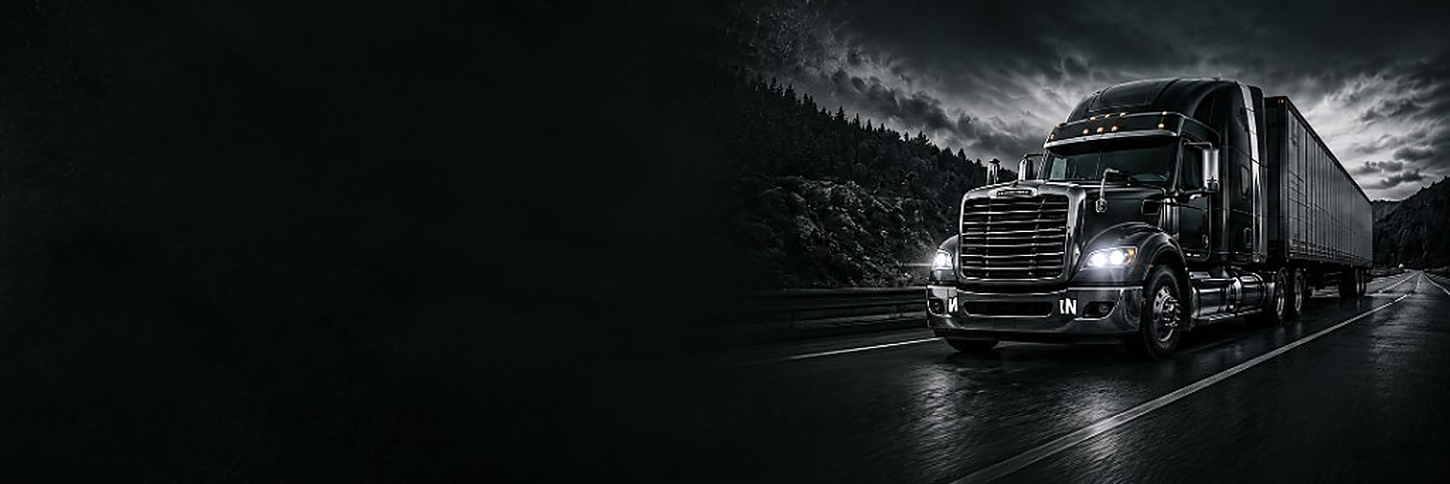 Black heavy-duty truck and trailer under a stormy sky